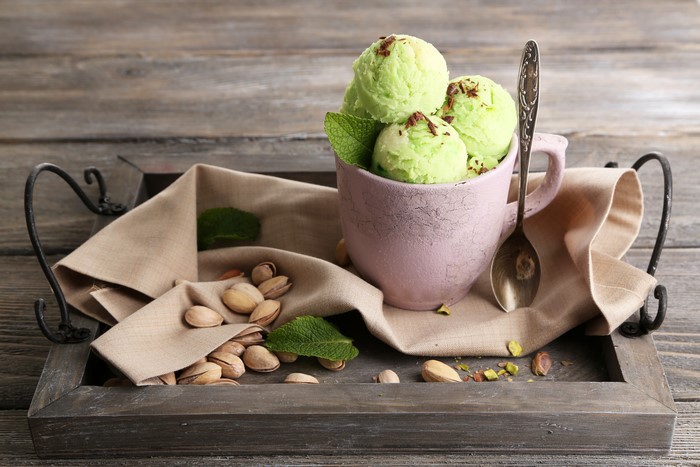 Pistachio ice cream with pistachios and mint on a tray