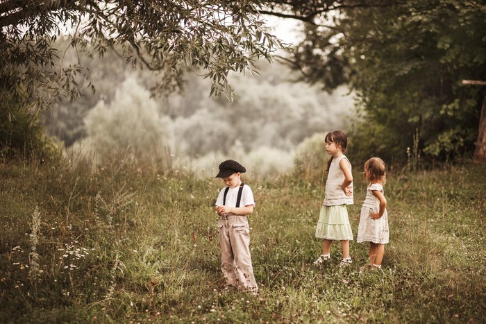 Three children in a grassy field