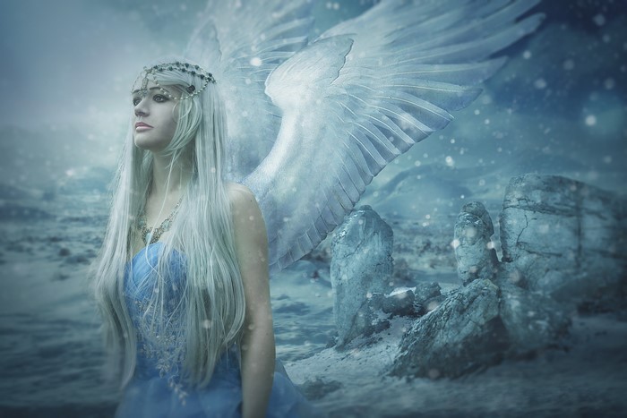 Angel with white wings in a snowy landscape