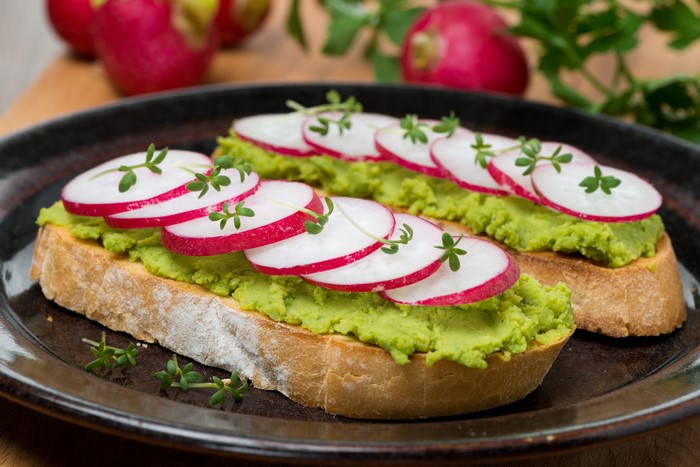 Two slices of bread with mashed peas and radishes