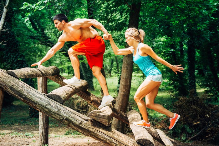 Man and woman doing obstacle course in forest