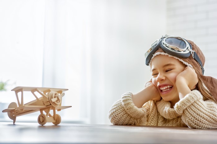 Girl in pilot hat with toy airplane