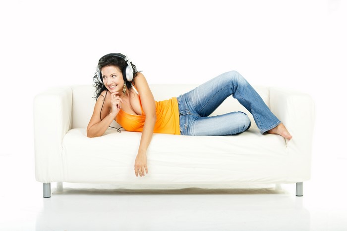 Brunette girl with headphones on a sofa