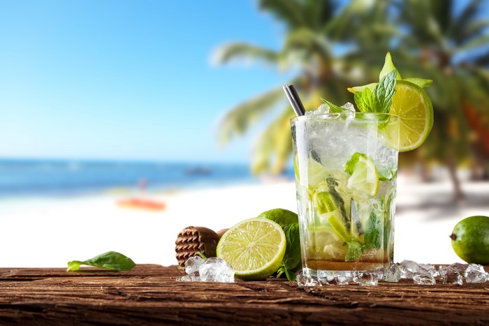 Mojito cocktail with limes and mint on a beach