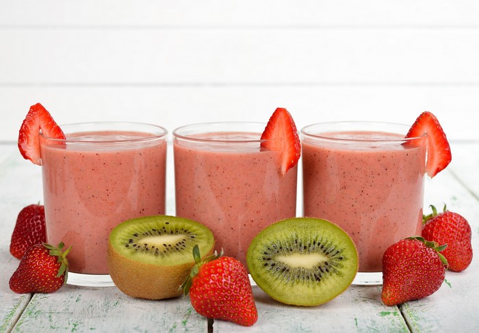 Three strawberry kiwi smoothies in glasses with fruit