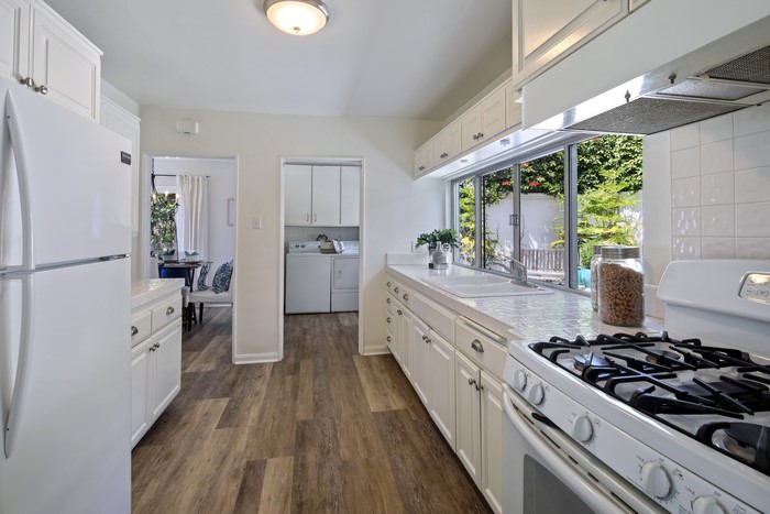 Kitchen with white cabinets, appliances, and window view