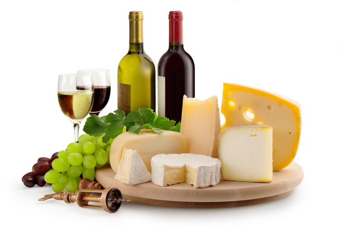 Still-life of wine, grapes, and cheese on a cutting board