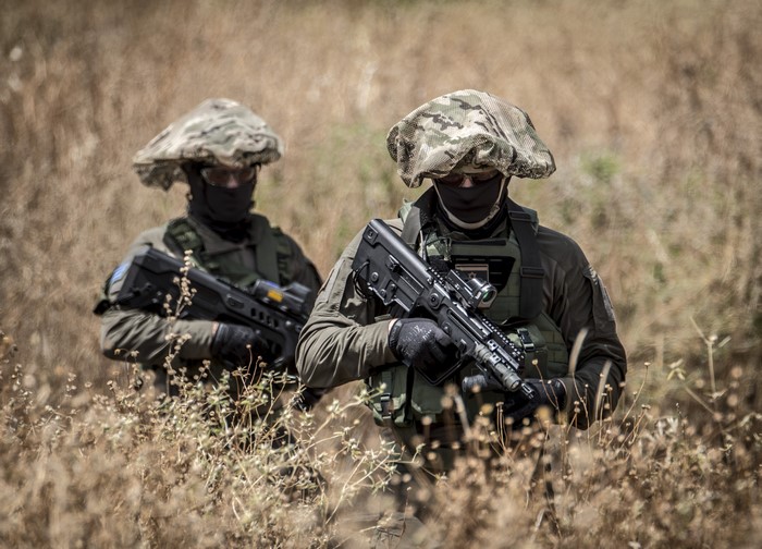 Two soldiers with assault rifles in camouflage