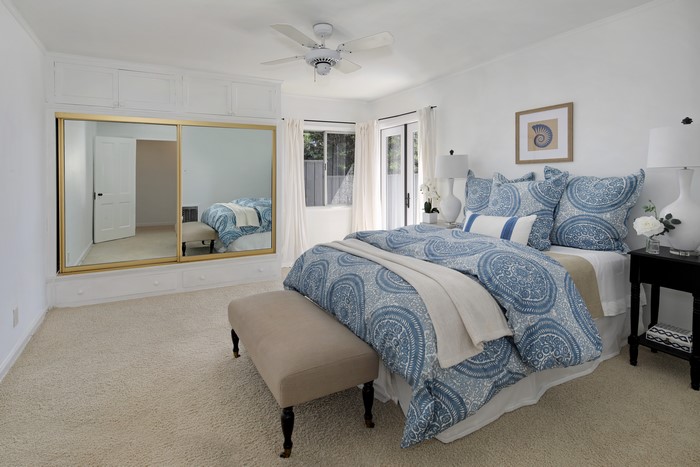 Bedroom with mirrored closet and blue patterned bedding