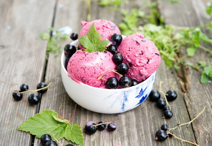 Blackcurrant ice cream in a bowl with fresh berries