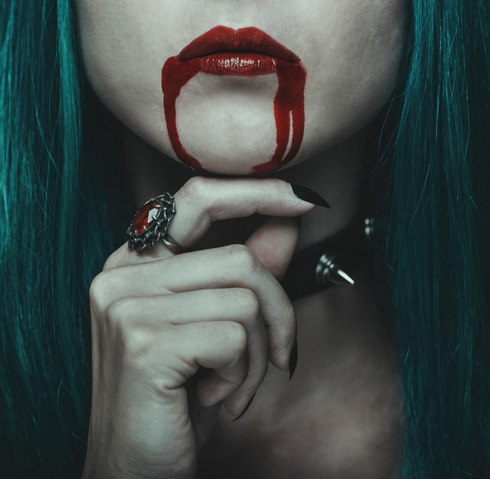 Woman with blood dripping from lips and gothic ring