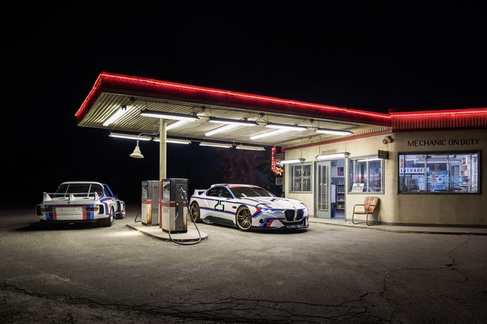 Two BMW M4 CSL cars at a retro gas station at night