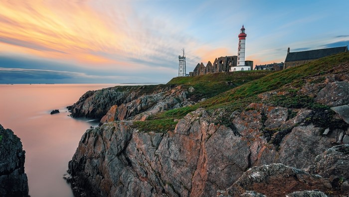 Lighthouse and ruins on a rocky coast at sunset, Saint Mathieu, France