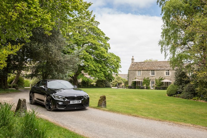 Black 2017 BMW M4 Coupe parked in front of a stone house