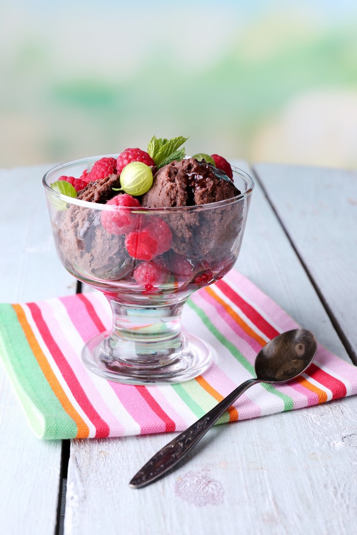 Chocolate ice cream with raspberries and gooseberries in a glass bowl