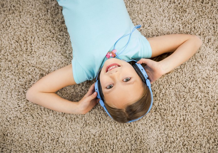 Girl with headphones lying on carpet