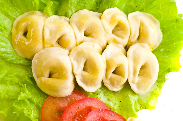 Pelmeni on lettuce with tomatoes