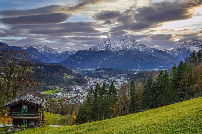 Wooden cabin overlooking Bavarian town and snow-capped mountains