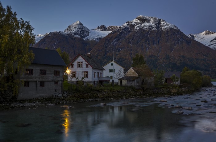Houses by river with mountains at dusk