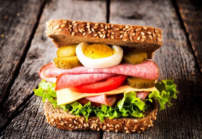 Sandwich with sausage, egg, pickles, and lettuce