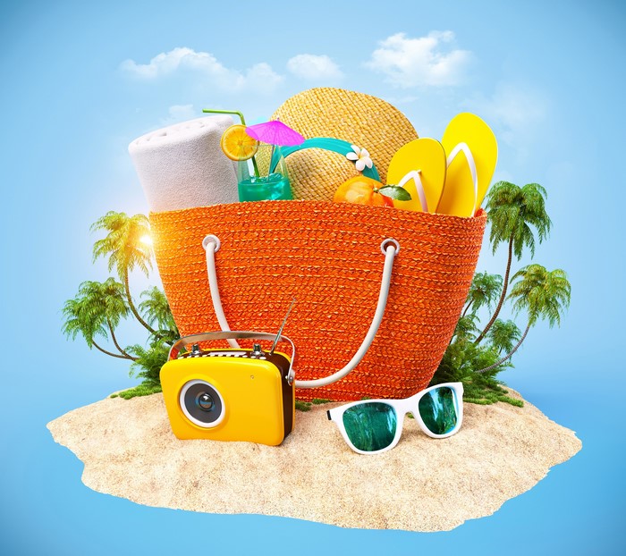 Beach bag with summer accessories on a tropical island