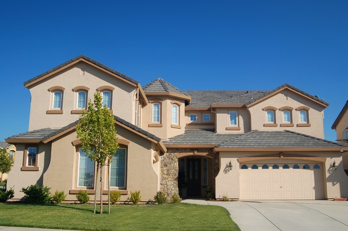 Large tan house with garage and trees
