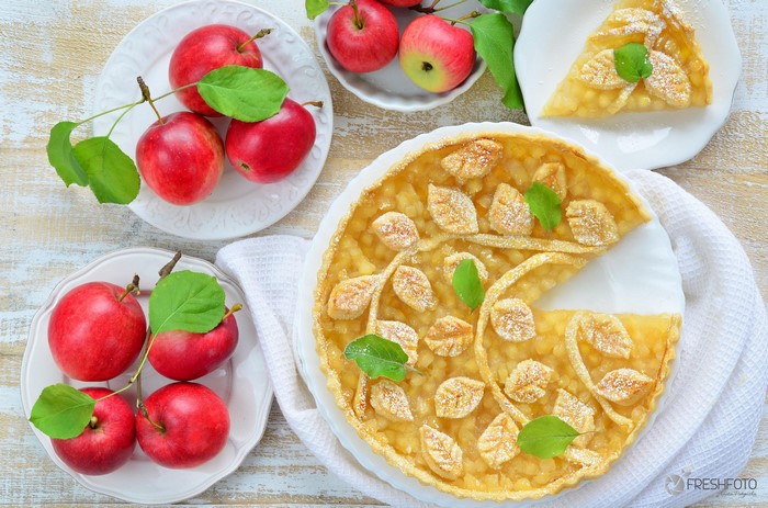 Apple pie with decorative crust and fresh apples