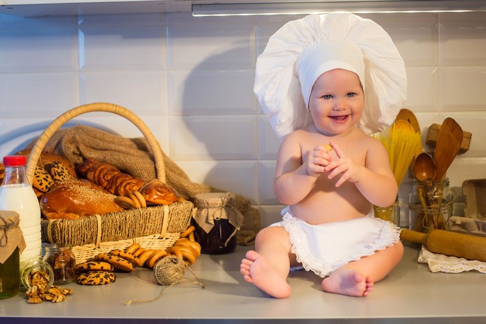 Baby in chef hat with baked goods