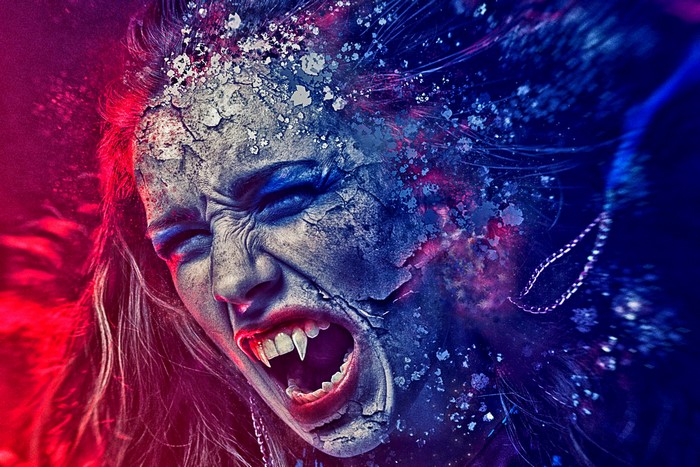 Woman with fangs screaming, cracked skin, red and blue lighting