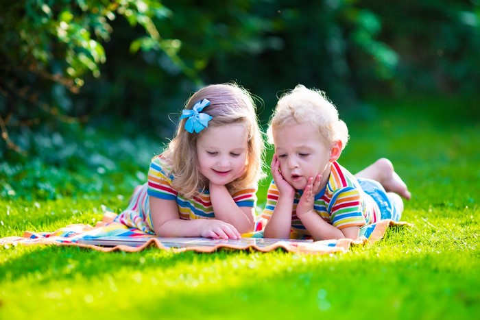 Two children reading on grass