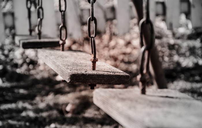 Close-up of a rusty swing chain and wooden seat