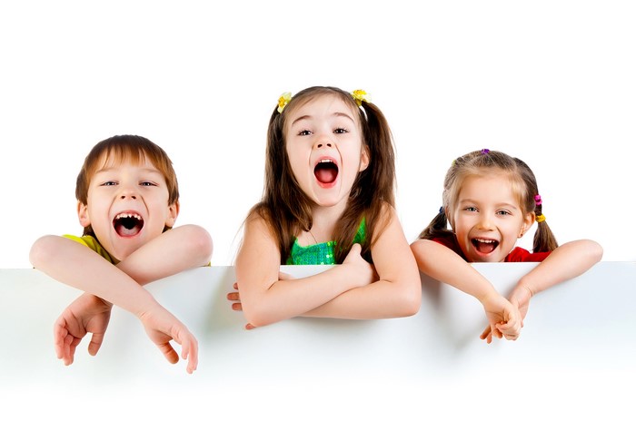 Three children peeking over a white surface