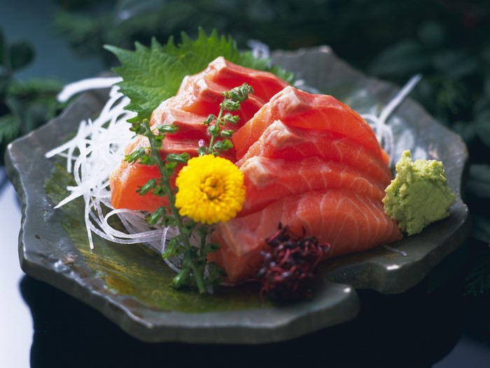 Salmon sashimi with wasabi and garnish on a plate