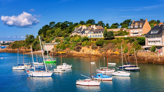 Sailboats in a harbor with houses on a hill in Brittany, France