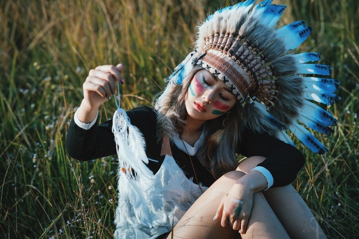 Woman in Native American Headdress holding Dreamcatcher