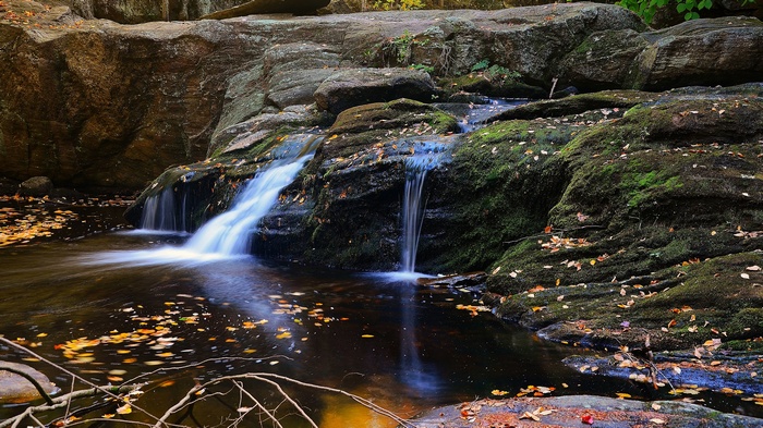 Waterfall cascading over mossy rocks in autumn