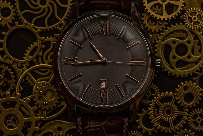 Close-up of a watch with Roman numerals and gears