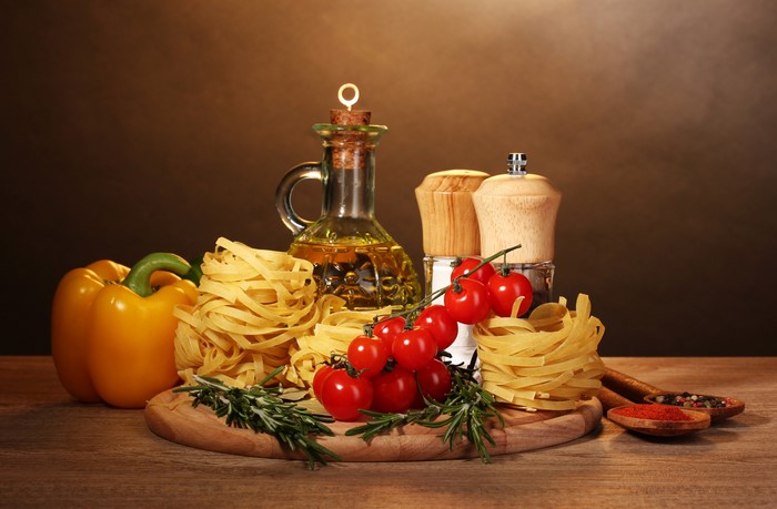 Still-life of Italian ingredients: pasta, tomatoes, bell pepper, olive oil, and spices