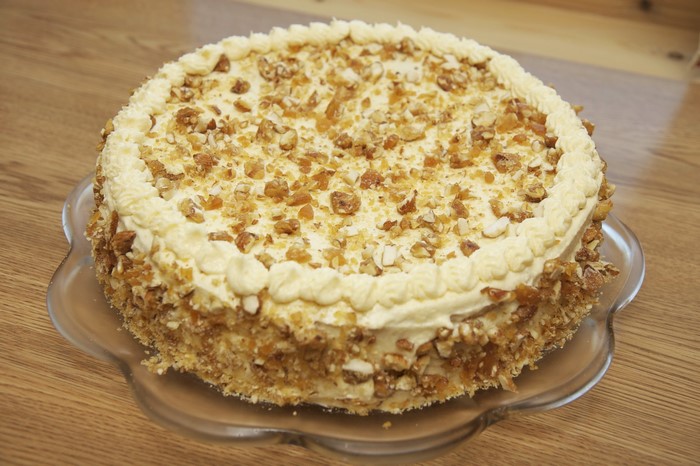 Round cake with cream and nuts on a plate