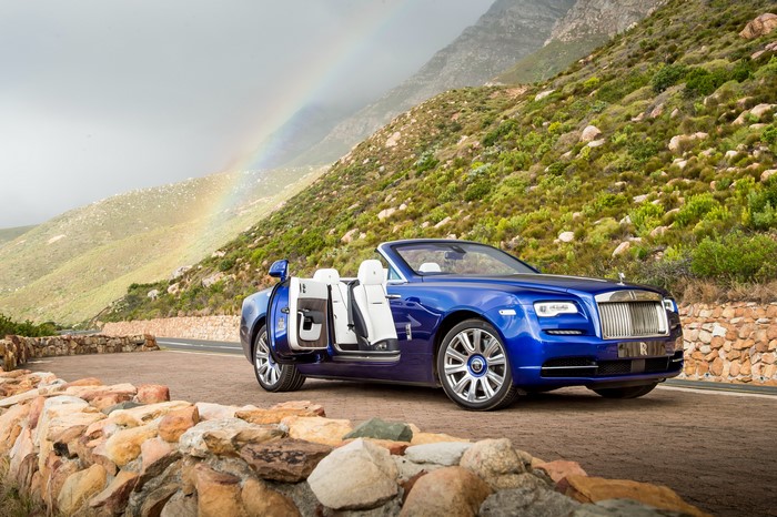 Blue Rolls-Royce Cabriolet on a Coastal Road with Rainbow