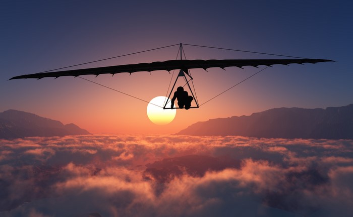 Hang gliding over clouds at sunset