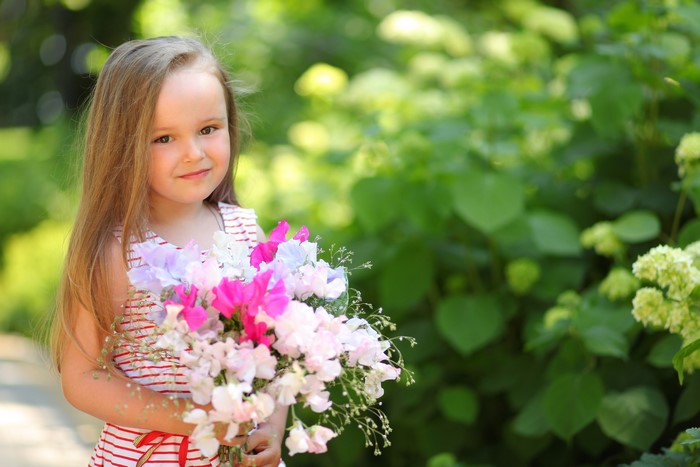 Little girl with dark blonde hair holding a bouquet