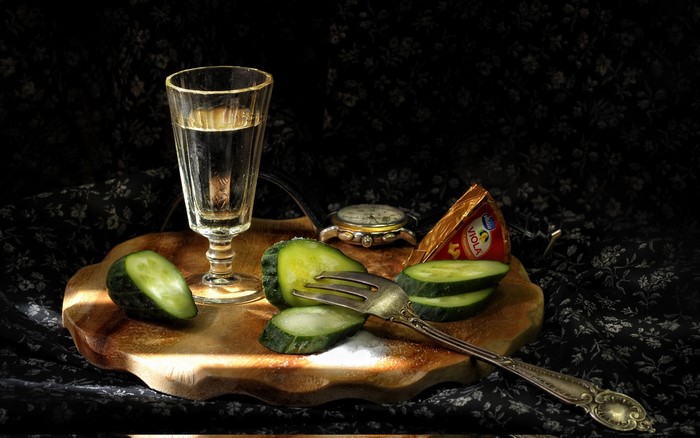Vodka, Cucumbers, Cheese, and Watch on a Cutting Board