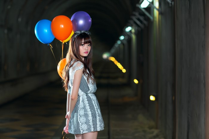 Asian girl with balloons in a tunnel