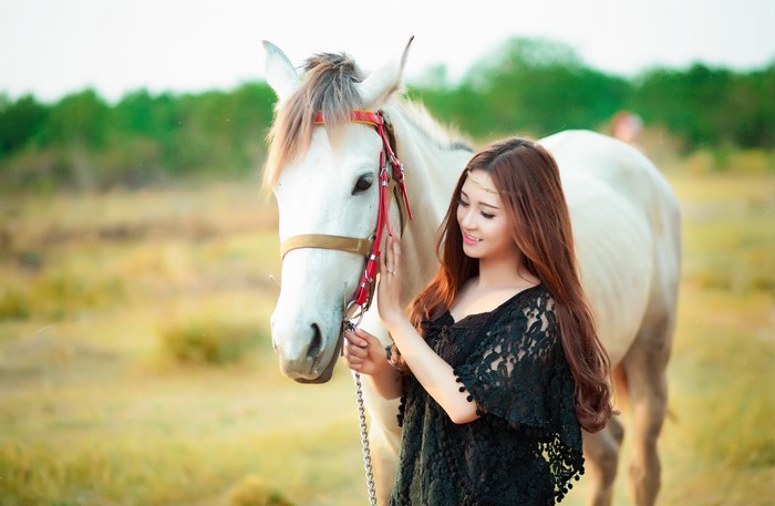 Young woman with brown hair and a white horse