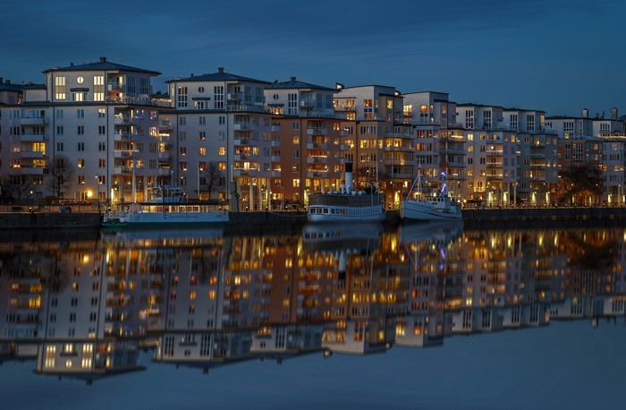 Apartment buildings and boats reflected in water at dusk in Stockholm, Sweden