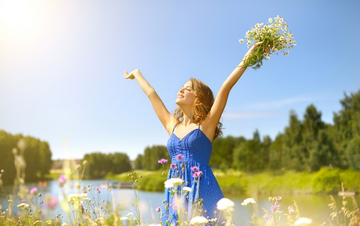 Blonde girl in blue dress holding camomiles