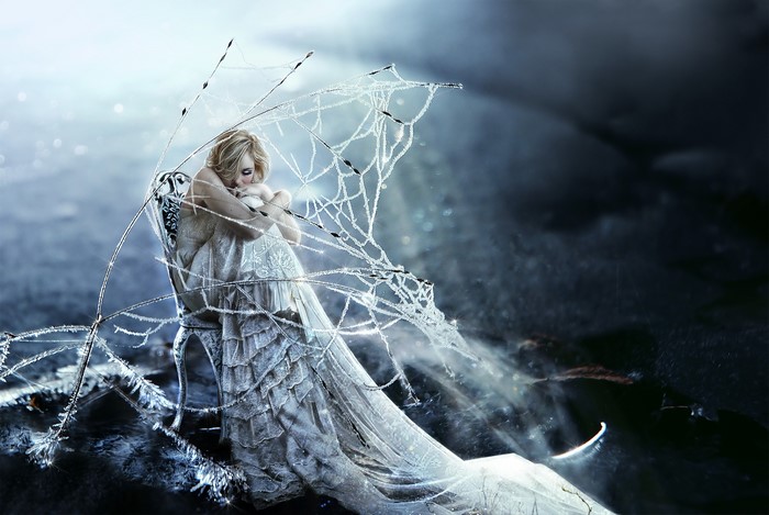 Woman in a white dress sitting on a chair covered in ice