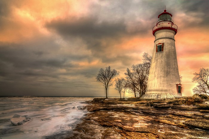 Marblehead Lighthouse on rocky shore during sunset
