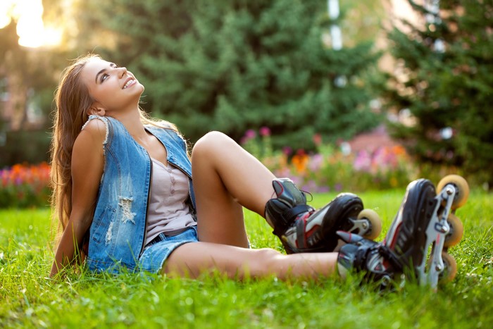 Woman with roller skates sitting on grass